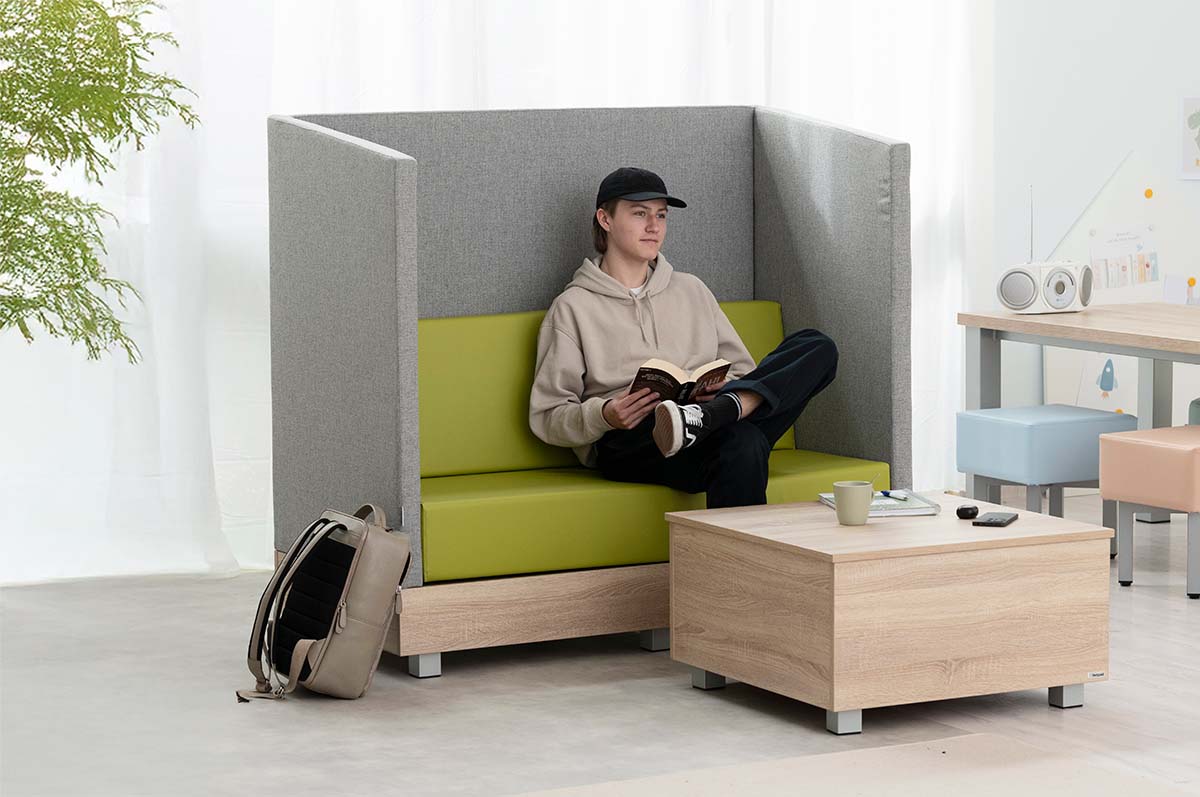 Chillo Schallschutzsofa mit Chillo Couchtisch und jungem Mann in Lehrerzimmer-Setting