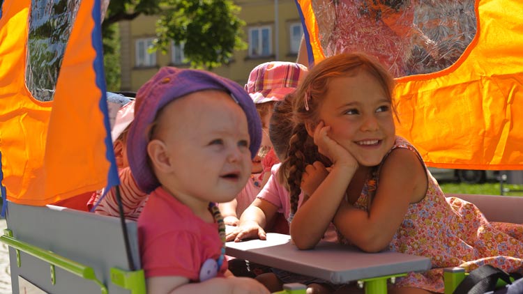 Kinder sitzen in einem Krippenwagen von Betzold.