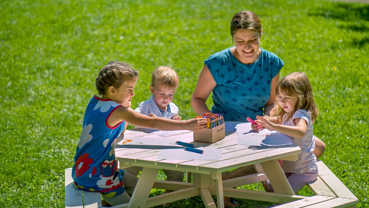 Erzieherin sitzt mit Kindern an einer Sitzgruppe aus dem Betzold-Onlineshop