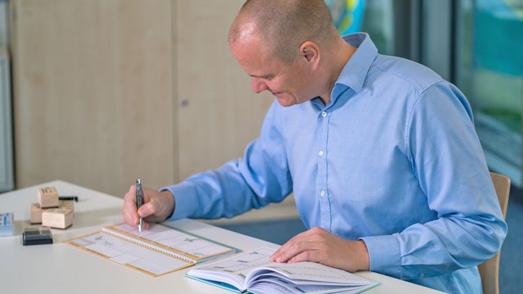Lehrer schreibt in Schulplaner