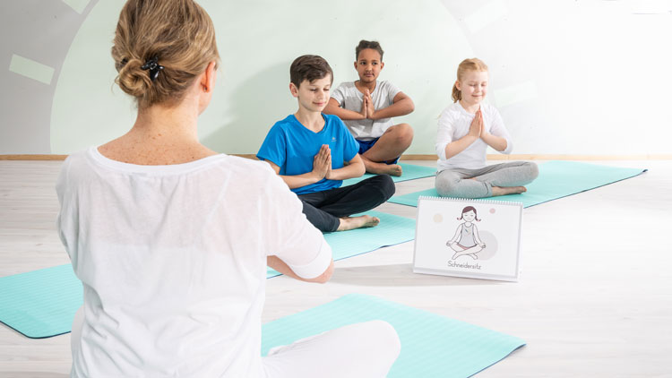 Kinderyogalehrerin mit Kindern im Lotussitz