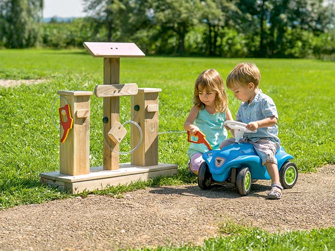 Betzold Tankstelle im Grünen mit 2 Kindern und einem Bobbycar