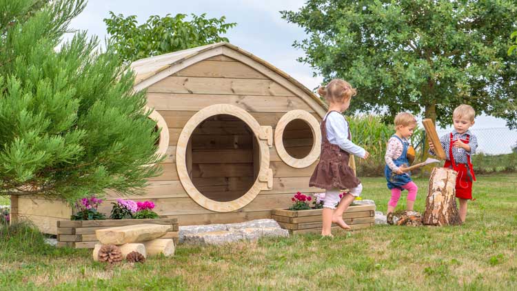 Kinder spielen im Garten vor einem Spielhaus von betzold.de