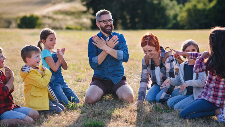 Lehrer und Kinder sitzen draußen im Kreis