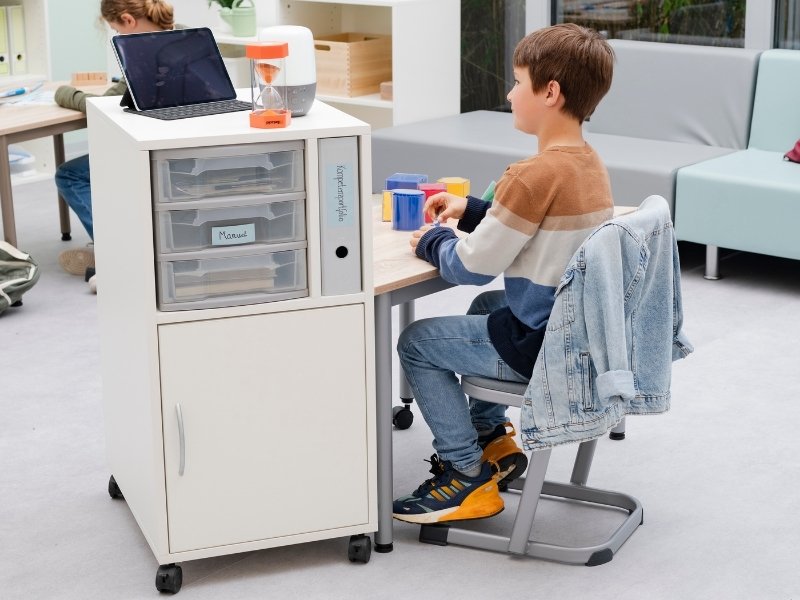 Junge am Schreibtisch mit kleinem Schrank als Aufbewahrungslösung