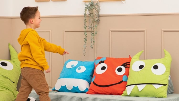 Kind zeigt auf 3 Kissen, die Gefühle darstellen
