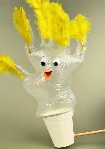 Küken aus einem Handschuh gebastelt, das aus einem Pappbecher schlüpft.