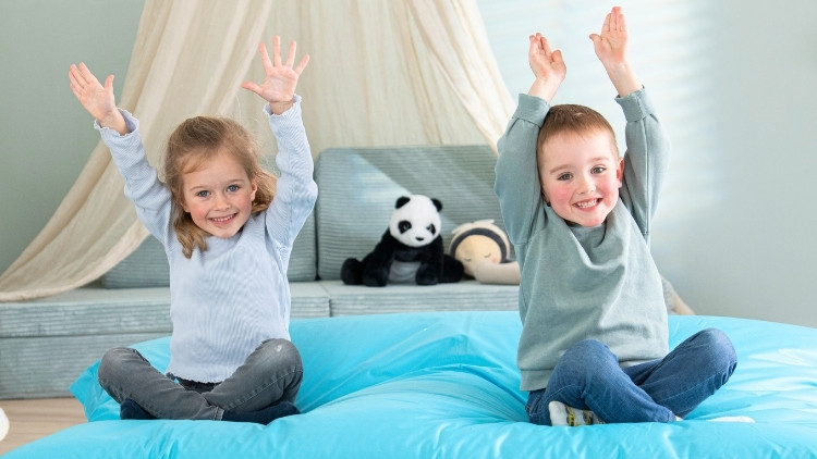 2 Kinder sitzen auf einem blauen Sitzsack von Betzold.