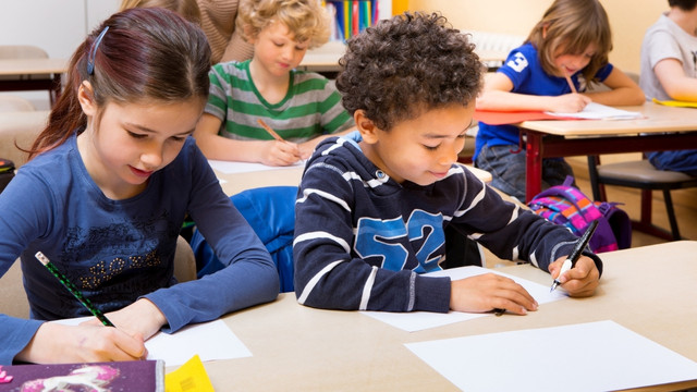 Kinder sitzen im Unterricht und schreiben