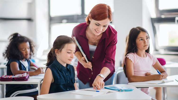 Lehrerin zeigt Schülerin etwas im Heft