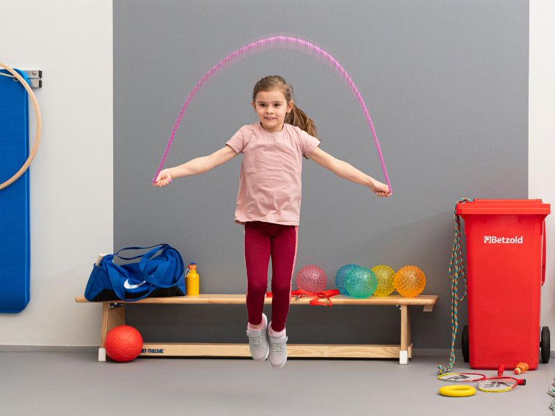 Mädchen trainiert mit Springseil in Sporthalle