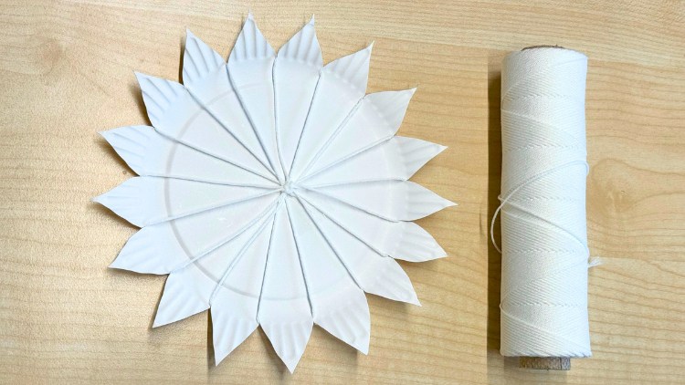 Schritt zwei, wie aus einem Pappteller ein Webrahmen entsteht, das Kettgarn wird in die Einschnitte aus Schritt eins gefädelt.