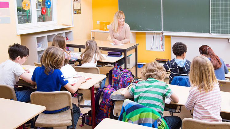 Lehrerin sitzt an Lehrerpult