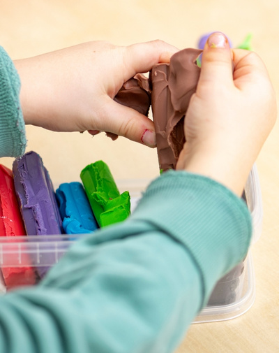 Kinderhände spielen mit bunter Knete