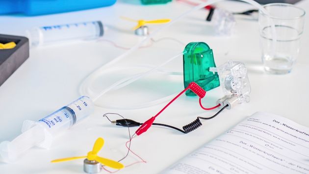 Versuchsaufbau eines Dynamos auf einem Tisch mit Material aus dem Experimentierkoffer