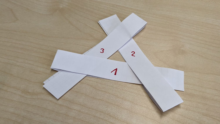 3 Papierstreifen mittig gefaltet und ineinandergeschoben - so entsteht ein Mini-Windrad.