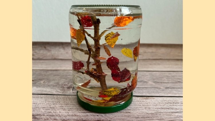 Eine herbstliche Schneekugel aus einem Einmachglas und Pailletten in Laubform.