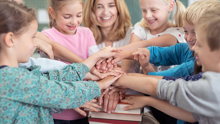 Lehrerin und Schüler legen Hände aufeinander
