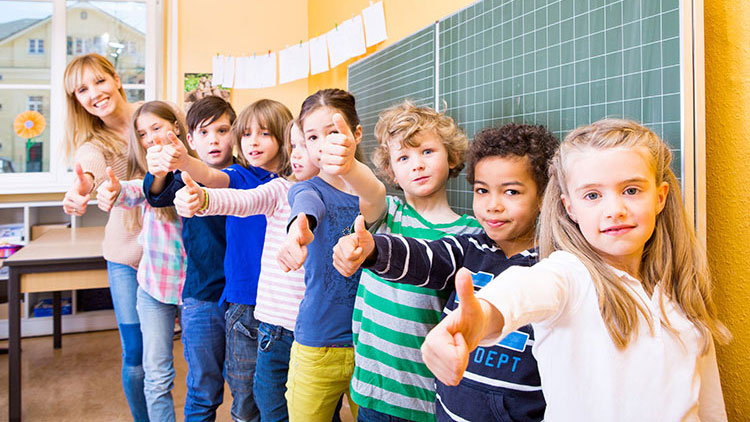 Schüler stehen mit Lehrerin vor Tafel