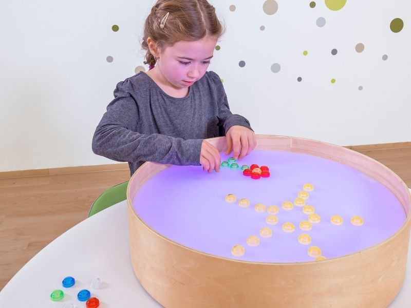 Kleines Kind schaut durch die bunte Folie des Optik-Entdeckersets