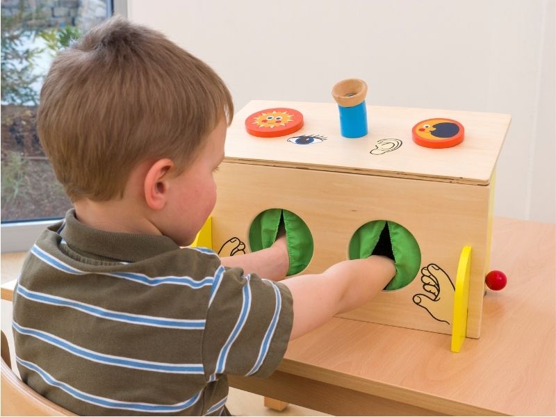 Junge hat beide Hände in einer Fühl-Box