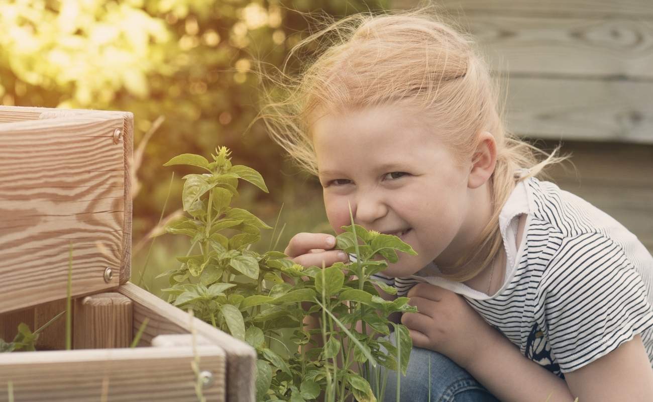 Mädchen im Garten riecht an einer Pflanze