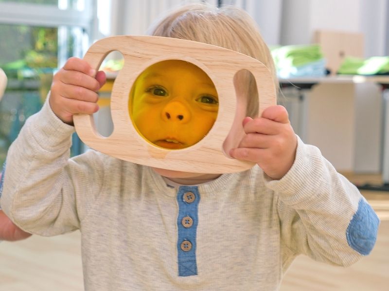 Kleines Kind schaut durch die bunte Folie des Optik-Entdeckersets