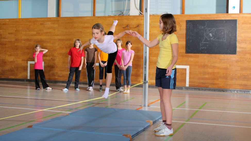 Kinder nutzen im Schulsport eine Slackline