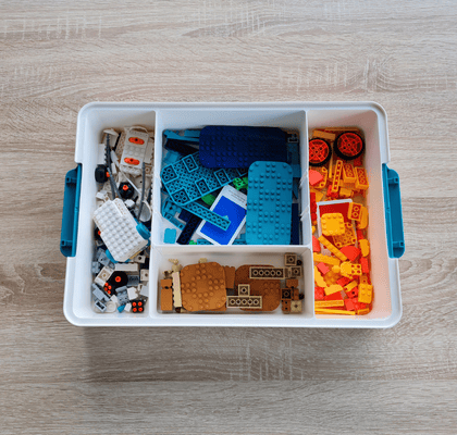 Draufsicht auf das innere der Box mit 4 Fächern und darin farbig sortierten Teilen