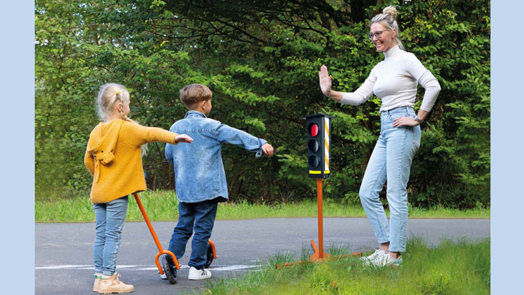 Lehrerin hält Kinder an einer roten Ampel an
