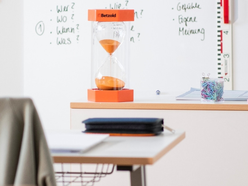 große orangene Sanduhr steht auf dem Lehrerpult