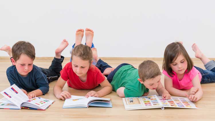 Kinder lesen auf dem Boden liegend