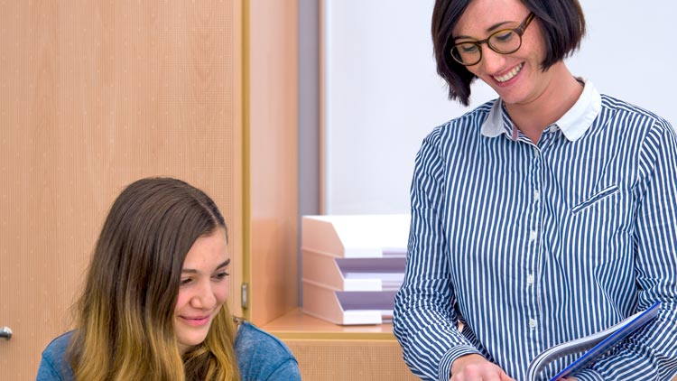 Lehrerin zeigt Schülerin den Schulplaner