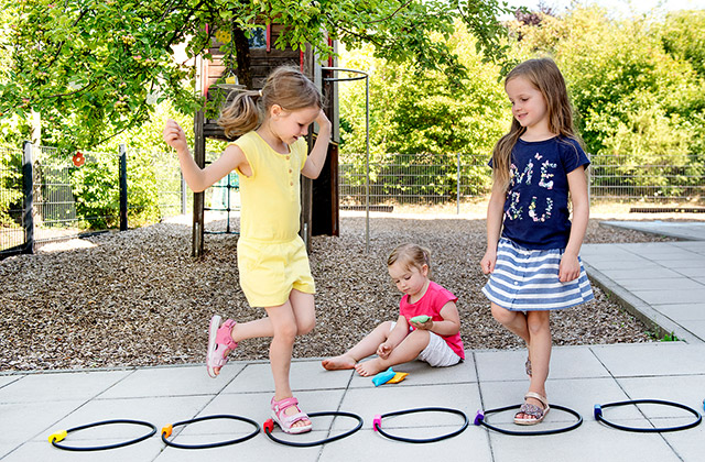Kinder spielen Hüpfspiel im Garten