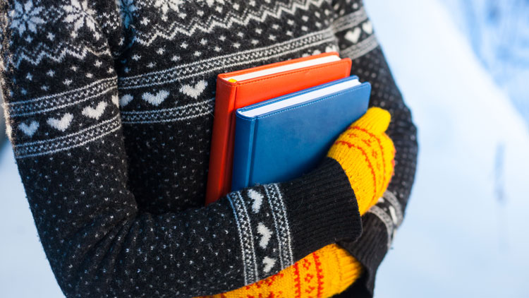 Schülerin mit Büchern im Winterpullover