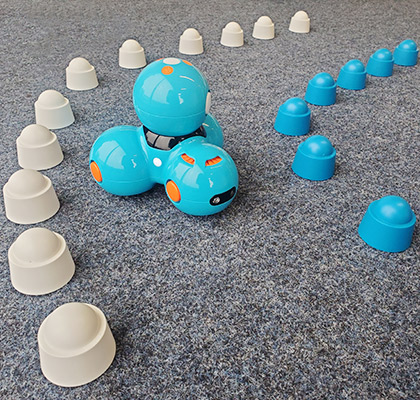 Dash-Roboter fährt durch eine Parkour auf dem Teppichboden