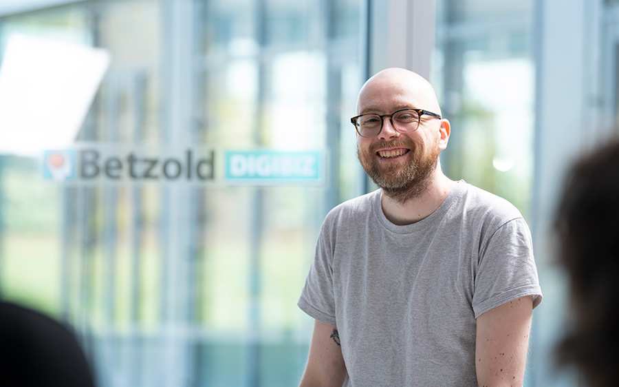 DIGIBIZ-Trainer sitzt vor einem Publikum und lächelt