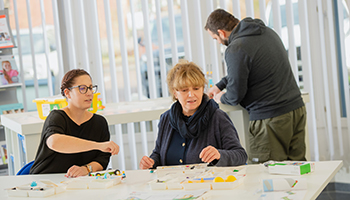 Zwei Personen sitzen am Tisch und programmieren mit LEGO Education