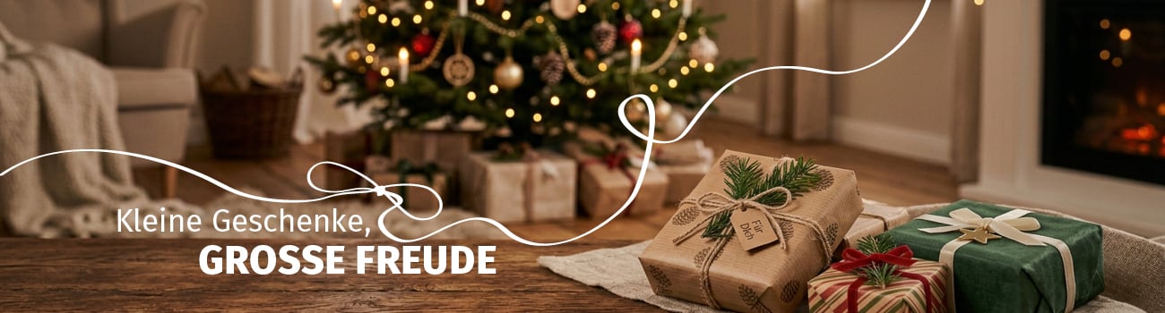 Liebevoll verpackte Weihnachtsgeschenke mit Schleifen und Tannenzweigen auf einem Holztisch vor einem geschmückten Weihnachtsbaum.