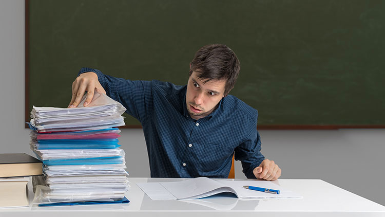 Lehrer mit großem Stapel Klassenarbeiten