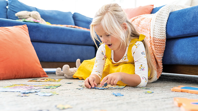 Kind puzzelt auf Teppichboden