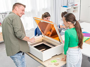 Lehrer unterstützt Schülerin beim Arbeiten mit dem Plotter
